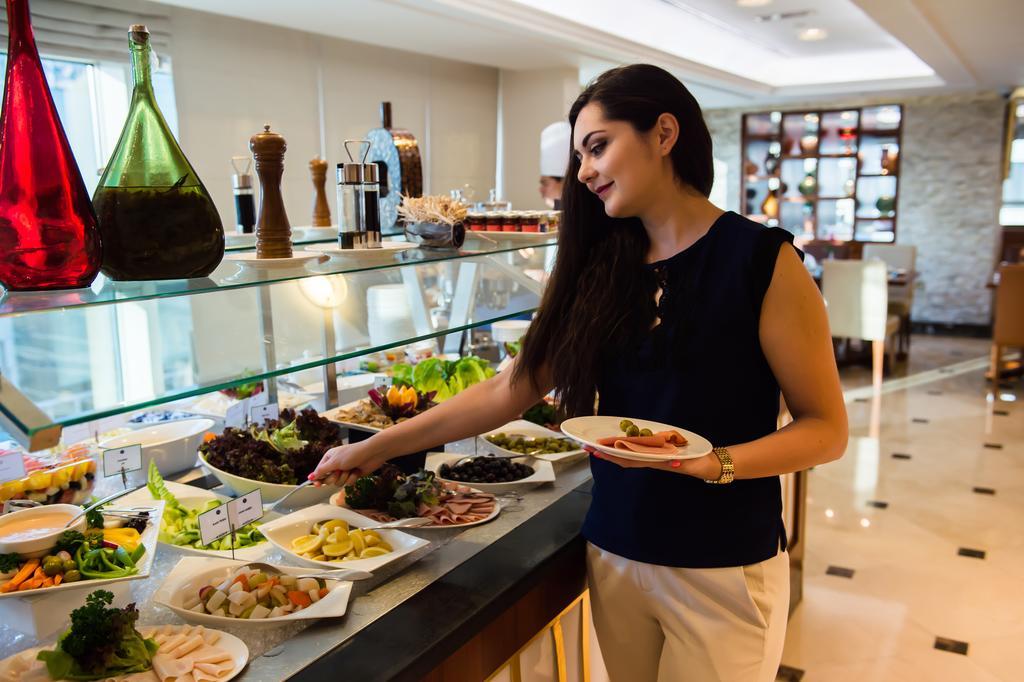 Grand Mercure Majlis Residences Abu Dhabi Luaran gambar A woman selecting food from a buffet